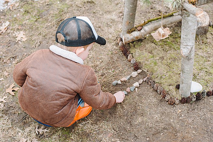 fairy house with pine cone perimeter and rock lined walkway